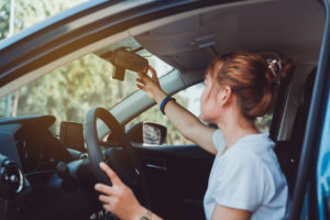 La donna che guida in sicurezza regola ogni volta lo specchietto retrovisore dell'auto all'interno prima di iniziare il viaggio.