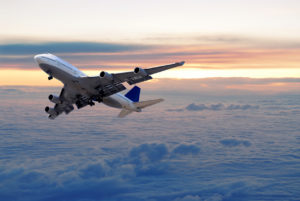 Big passenger airplane flying above the clouds and sunset