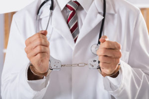 Close-up Of Arrested Doctor's Hand With Handcuffs
