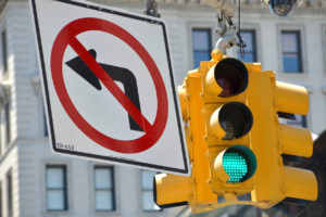Detail of a no left turn road sign and a hanging yellow traffic light