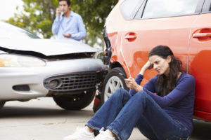 Female Driver Making Phone Call After Traffic Accident Sat Against Car.