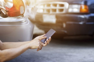 Hombre usando su smartphone al lado de la carretera después de un accidente de tráfico