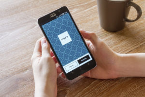 man hand holding screen shot of Uber application showing on Asus Zenfone 2 mobile phone.