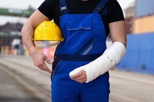 Adult with a workplace injury holding a broken arm, visibly in pain.