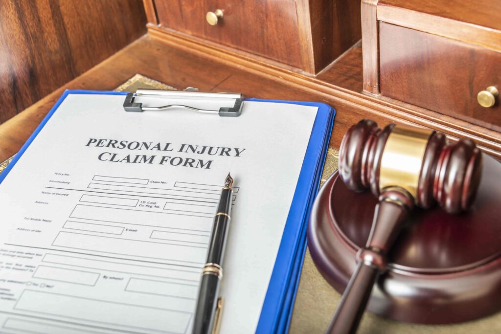 Personal injury claim form on a clipboard with a pen and judge’s gavel on a wooden desk, representing legal claims and injury compensation.