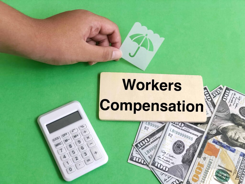 Workers’ compensation insurance concept with calculator, cash, and umbrella protection icon, representing employee benefits, wage replacement, and workplace injury coverage. Workers’ compensation insurance concept with calculator, cash, and umbrella protection icon, representing employee benefits, wage replacement, and workplace injury coverage.