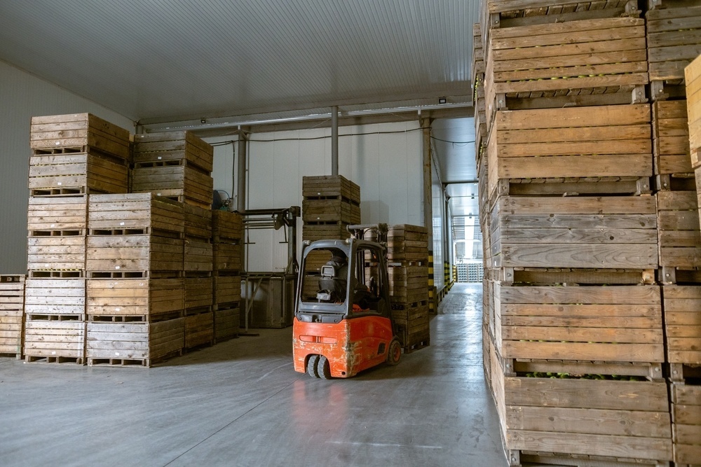 Forklift parked between stacked wooden crates in a warehouse